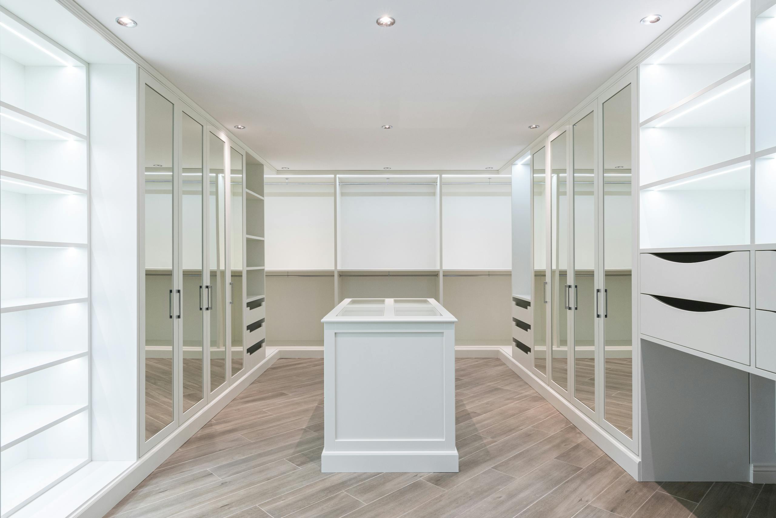 walk in closet with empty shelves and mirrored doors